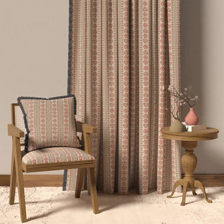 The Sarangi Fringes curtain displayed in a room setting with a wooden chair and table, demonstrating its full-length and bohemian style.