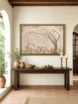 The Secret Garden embroidered wall art, framed in gold, displayed above a wooden console in a Mediterranean-style entryway with terracotta pots and candlesticks.
