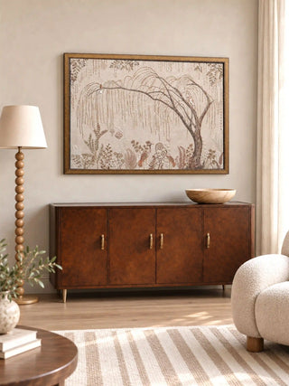The Secret Garden embroidered wall art, framed in gold, displayed above a burl-wood console styled with a floor lamp and a boucle armchair.