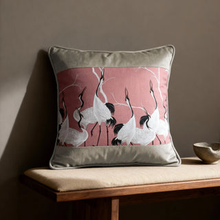 Single Sedge Poised Cranes Cushion displayed on a wooden bench against a grey wall.