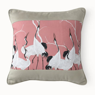Full studio view of the Sedge Poised Cranes Cushion featuring the bird pattern on a pink base.