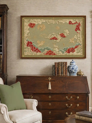 Framed Seraphim wall art in sage green above a secretary desk with leather-bound books and a blue and white ginger jar, beside a cream armchair with an olive cushion