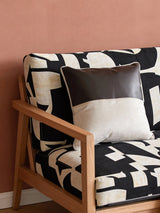 A luxury Serene Strokes Fusion cushion featuring a chocolate leather panel and cream velvet resting on a black and white patterned armchair.