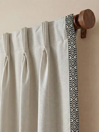 Close-up of the professional pinch-pleat tailoring and geometric border on a wooden curtain rod.