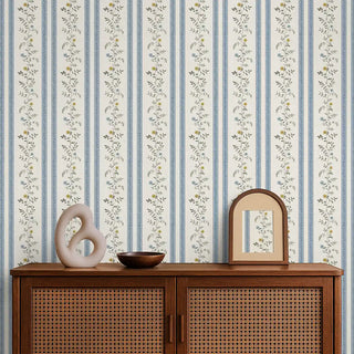 Blue & beige floral stripe wallpaper behind a wooden console with a sculptural vase and mirror, creating a calm setting.