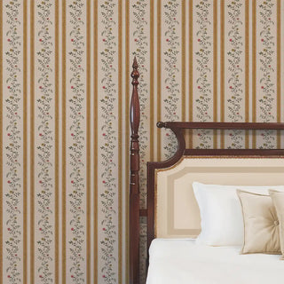Mustard & beige floral stripe wallpaper behind a traditional wooden bed with cream bedding, giving a warm and inviting feel.