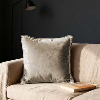 Single Serra Bloom Dew Cushion displayed on a beige sofa against a dark background.