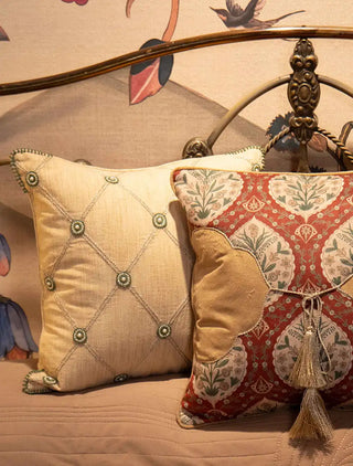 Styled close-up of the Shahzar cushion covers featuring beaded diamond lattice, red printed motifs, and gold tassels.