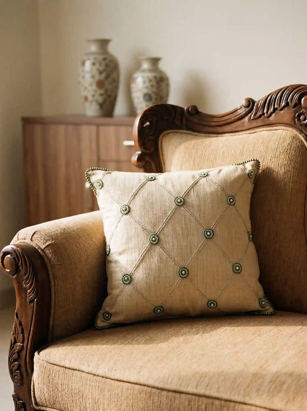 The Shahzar embroidered linen cushion cover styled elegantly on a classical carved wooden armchair panel in a warmly lit room.