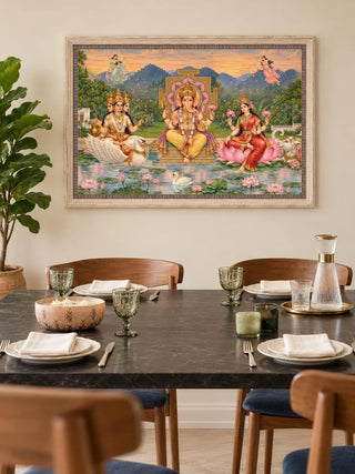 Framed Shree Lakshmi Ganesh Saraswati wall art in a whitewashed frame above a dark marble dining table set with plates and green goblets