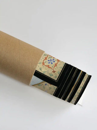 Shri Ram Parivar wall art in rolled packaging, the ivory floral border and gold detailing visible at the mouth of a kraft shipping tube