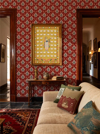 Shrinathji Pichwai art print framed on a red wallpaper wall in a vintage living room.