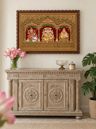 The Shriyam wall art, framed and hung above a whitewashed carved console table styled with pink lotus flowers and a crystal bowl.