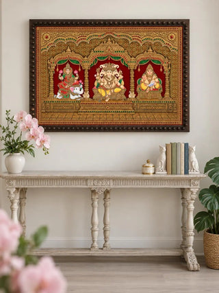 The Shriyam wall art, framed in a beaded dark wood frame and hung above a console table with pink orchids and cream books.