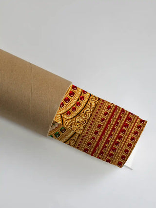 A rolled print of the Shriyam wall art showing a detail of its coordinating gold filigree arch border with red and green gem inlay.