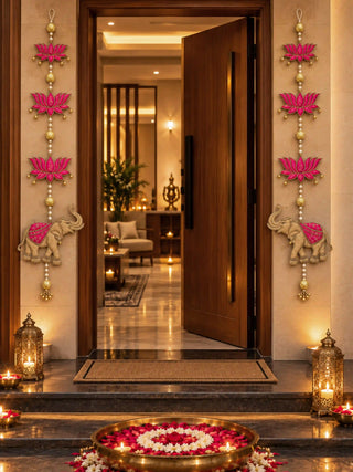 A pair of Shubh toran hangings either side of a doorway, three magenta lotuses and a gold elephant on pearl strings with bells.