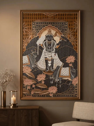 The Shyam Sundar embroidered wall art in a gold frame above a dark wood console styled with a glass candle hurricane and dried flowers.