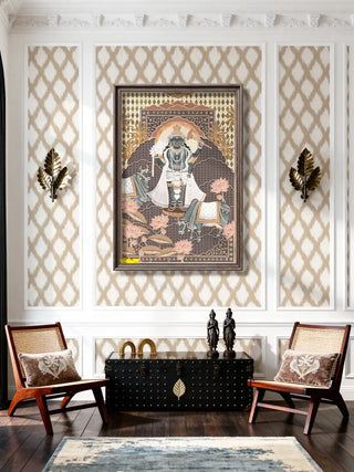 A large framed Shyam Sundar wall art piece displayed in a luxury living room with rattan chairs and ikat wallpaper.