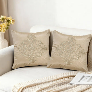 A pair of Silken Ornate cushions styled on a contemporary white sofa next to a vase of yellow flowers in a bright living room.
