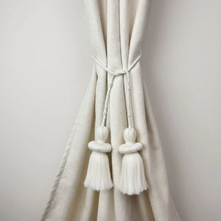 Silkstone Handcrafted Curtain Tieback secured on a cream curtain, showcasing the tiered ivory tassels with pearl bead accents.