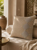 The Sirocco Moroccan arch cushion cover styled on a rich chocolate brown velvet sofa panel next to a modern tripod floor lamp.