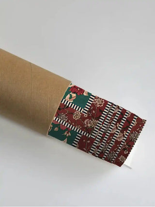 Sorena wall art in emerald rouge in its rolled packaging, slipped into a kraft shipping tube for safe delivery.