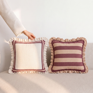 Pair of Spellbound Cinnamon pillows with maroon frame border on ivory and burgundy-cream stripes, both with hand-stitched ruffled cream edges in natural light.