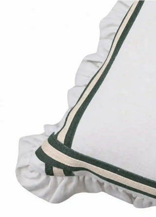Close-up corner detail of the Spellbound ruffle cushion cover in dark green, showing the woven tape border and the pleating of the ivory ruffle.