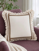 Spellbound Ruffle cushion cover in ivory and mocha placed on a plum velvet mid-century armchair beside a cream knitted throw and an indoor tree in a soft, light-filled living room