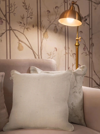 The Stardust cushion cover in ivory with an open-weave texture, ivory piping and scattered clear details, styled on a blush sofa.