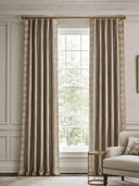 A pair of Storah taupe curtains styled symmetrically on a polished brass rod, perfectly framing a bright window in a neoclassical living room.