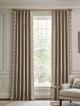 A pair of Storah taupe curtains styled symmetrically on a polished brass rod, perfectly framing a bright window in a neoclassical living room.