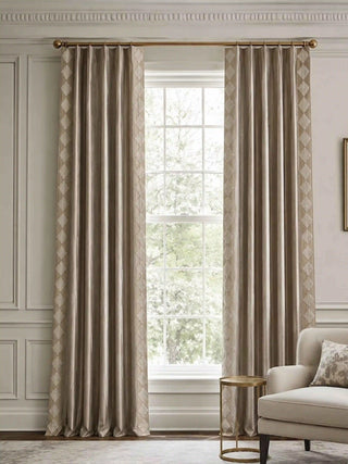 A pair of Storah taupe curtains styled symmetrically on a polished brass rod, perfectly framing a bright window in a neoclassical living room.