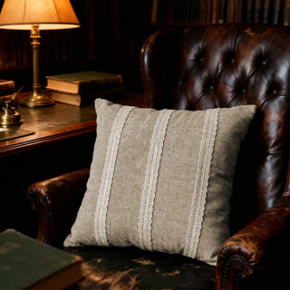 Single Stripe Lace Cushion displayed on a brown leather armchair in a cozy study setting.