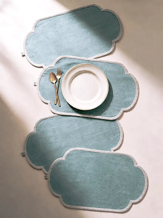 A flatlay of the Sufra table mats set of two in Powder Blue with gold cutlery and a white rimmed plate.