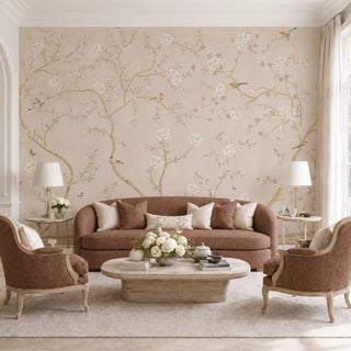 Sunset Serenade chinoiserie wallpaper in Blush Beige behind a curved sofa and armchairs in a living room.
