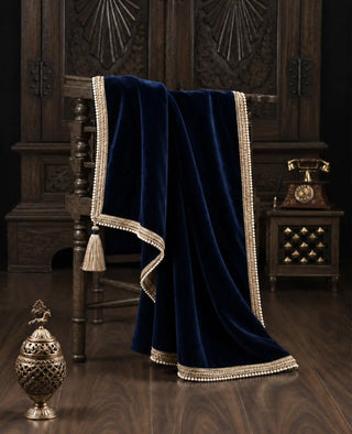 The Syahi sofa throw in Navy, view-antiquechair beside a brass urn and vintage telephone.