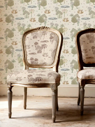 A pair of ornate vintage-style dining chairs upholstered in Taal Sepia fabric, styled in a bright, sun-drenched room.