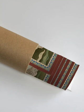 A section of the Tara Buddhist painting showing the intricate floral border partially unrolled from its protective shipping tube.