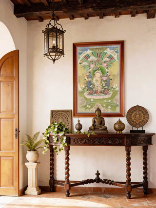 A serene meditation space featuring the Tara Buddhist painting mounted on a warm terracotta wall above a low wooden altar with incense.