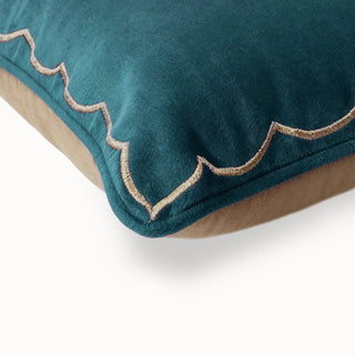 A high-definition close-up of the golden scalloped embroidery on the edge of the teal and tan velvet cushion.
