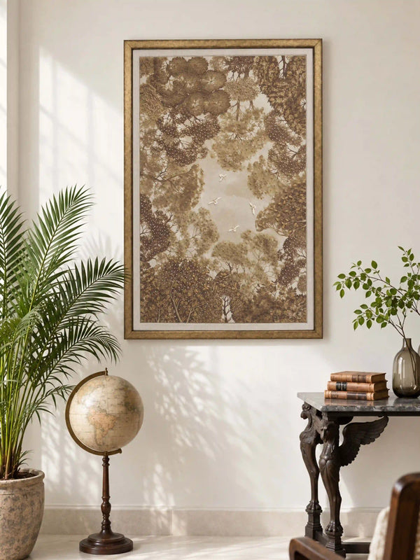 The Forest Nest embroidered wall art framed above a carved wood desk beside a vintage globe and a potted palm in a sunlit room.