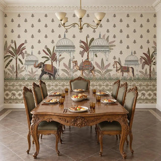 The Royal Caravan ivory wallpaper behind a carved walnut dining table with olive upholstered chairs and a brass chandelier, view-dining-room