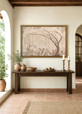 The Secret Garden embroidered wall art framed above a rustic wood console with terracotta vases and brass candlesticks in an arched entryway.