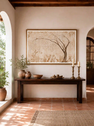 The Secret Garden wall art print in a light wood frame above a dark console with candlesticks and clay pots in an arched terracotta hall.