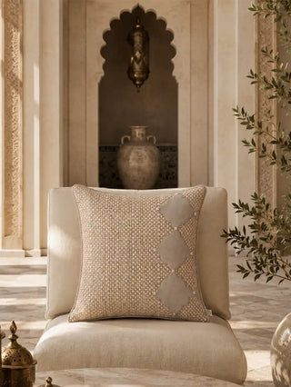 The Sirocco cushion cover styled on a cream armchair in a courtyard setting with an antique urn niche