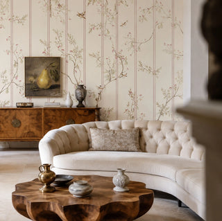 The Syntax of Spring custom chinoiserie wallpaper creating a soft romantic backdrop behind an off-white tufted chesterfield couch inside a luxury lounge hall.