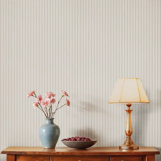 Thin Stripe Beige & Cream Wallpaper Roll in a living room setting, complemented by a wooden sideboard, ceramic vase with flowers, and a table lamp for a warm and welcoming decor.