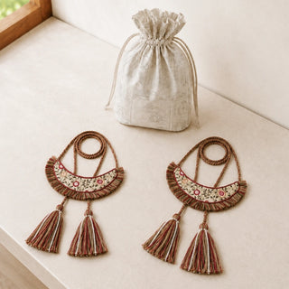 Thiya embroidered tiebacks laid out beside a printed cotton drawstring pouch on a light stone surface