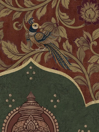 A detailed view of the Trideva Mangalam wall art showing a peacock among golden vines on a maroon ground, a scalloped green arch and the top of Ganesha’s crown.